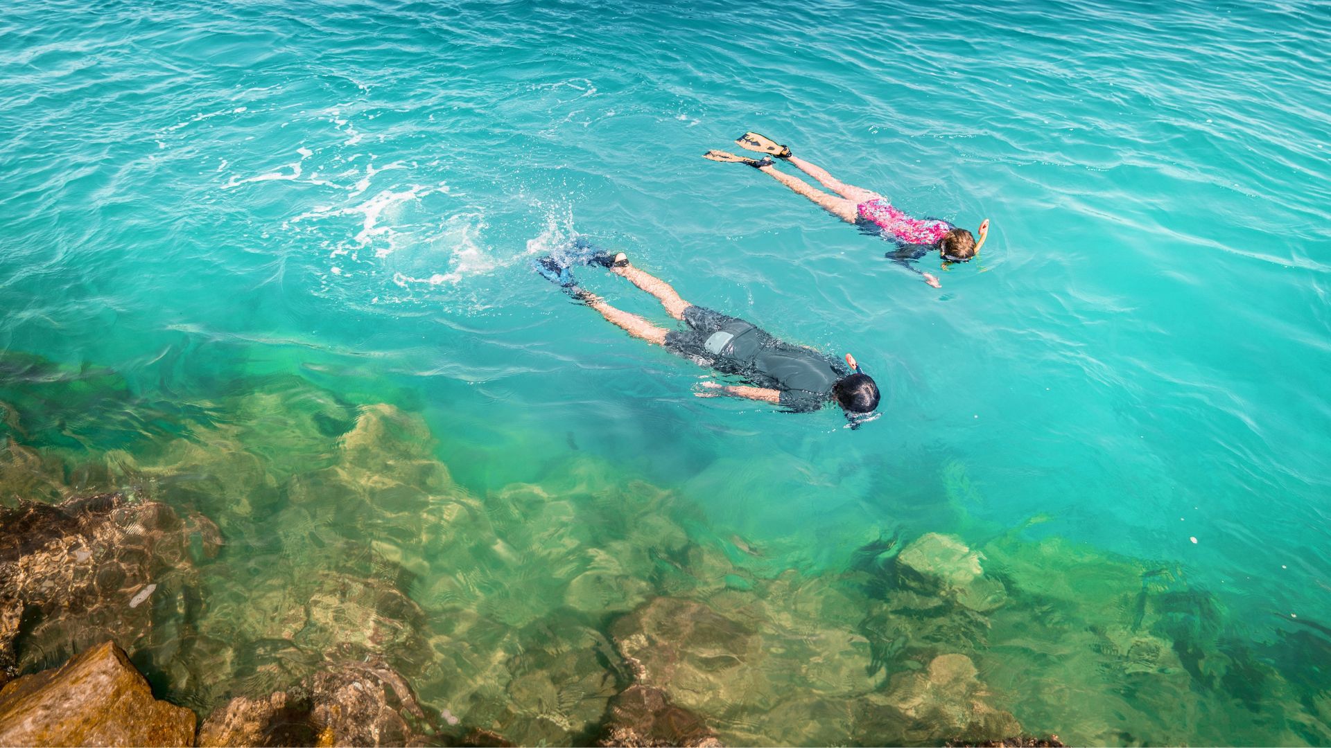 Kid and teenager snorkelling in shallow clear waters