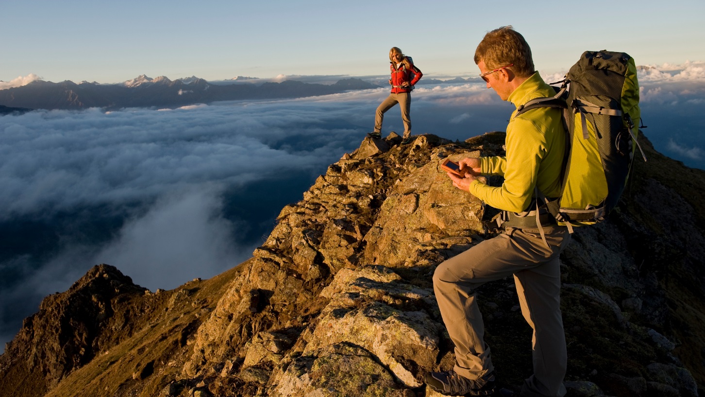 2 Hikers using a GPS tool at the peak of a mountain climb