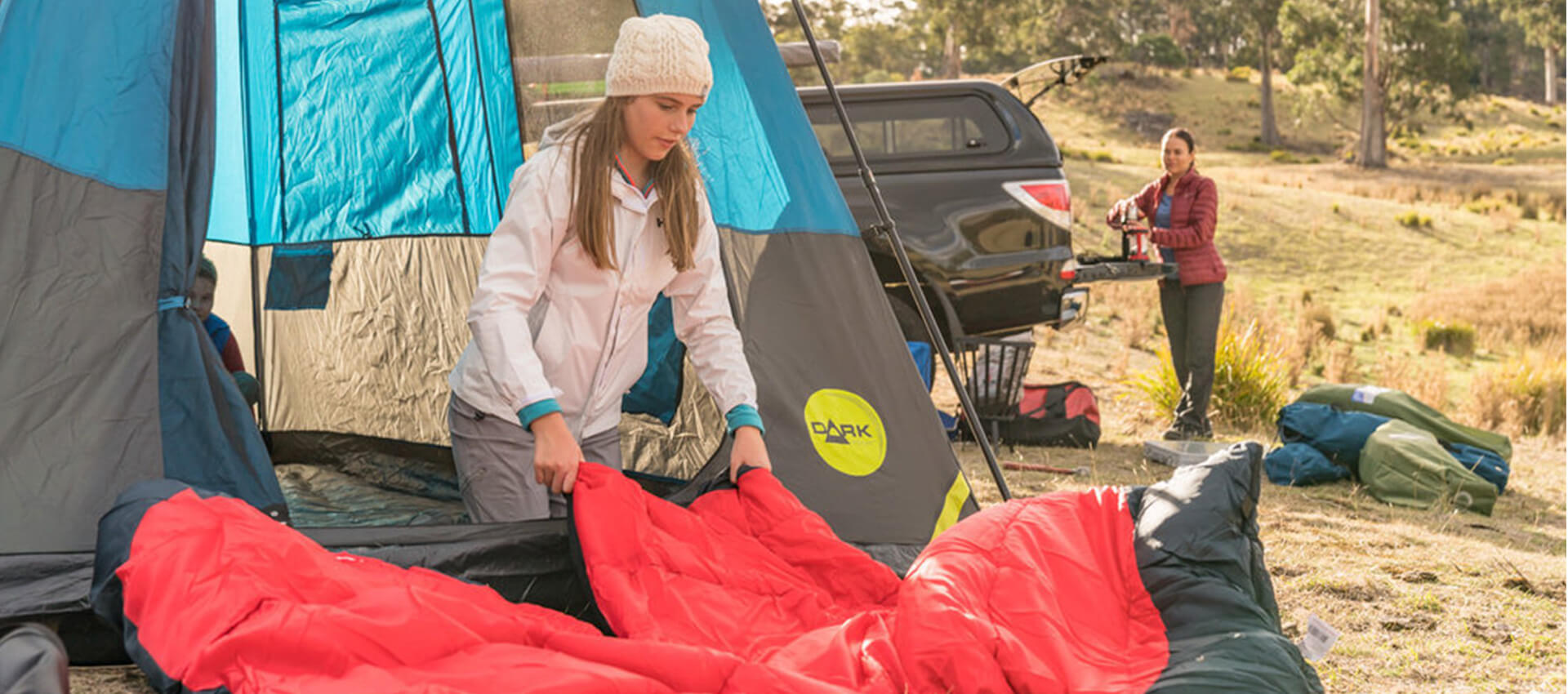 Woman fluffing out a sleeping bag for use in a pitched tent