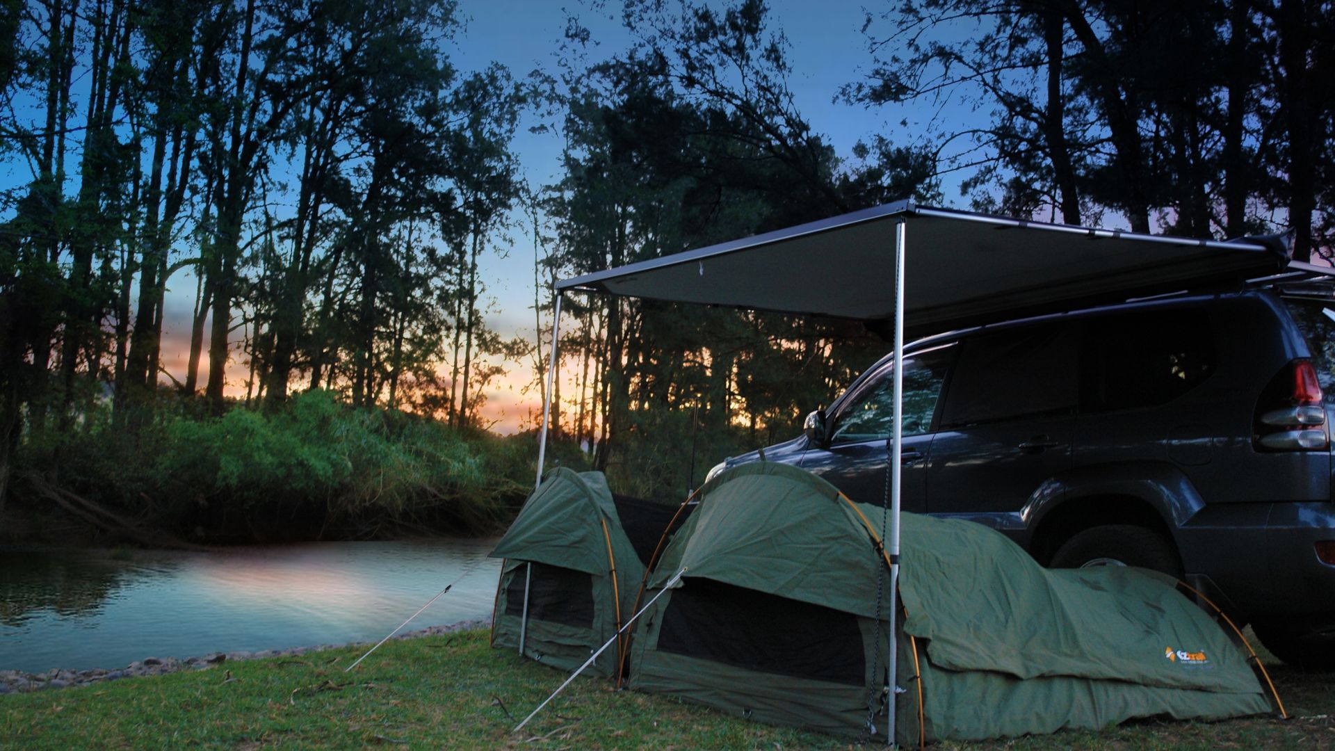A riverside set up of two OZtrail single swag under an awning